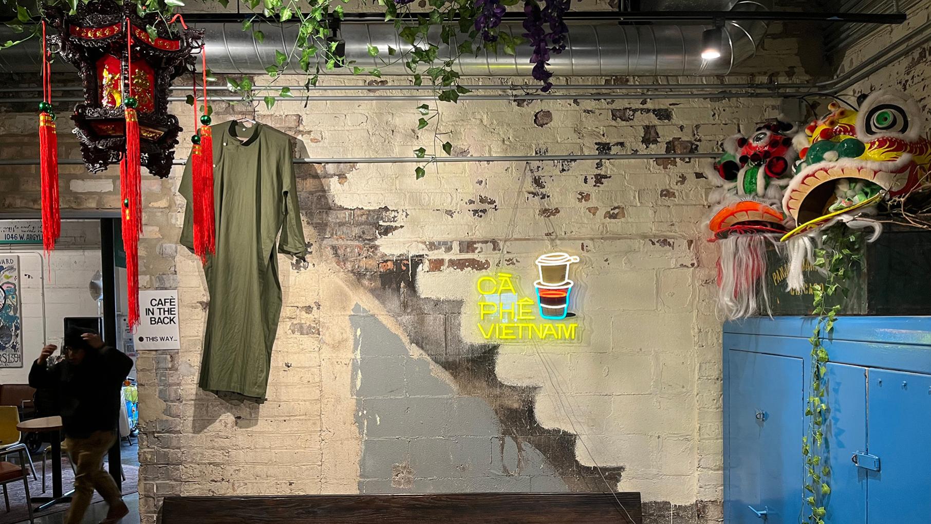 A brick wall with a neon sign and a lamp and shirt hanging in front of it and ivy above it